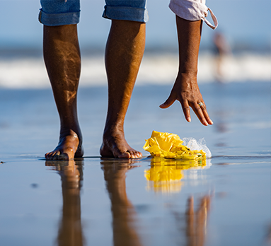 Person on the beach picking up trash